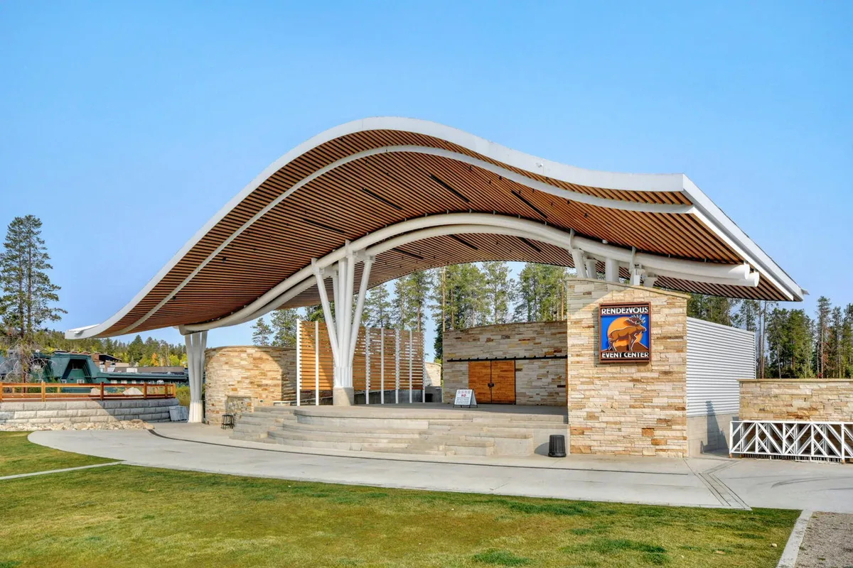 An open-air amphitheater with a curved roof, stone walls, and a broad open stage area awaits, set for outdoor performances and live music. The image captures the essence of Hideaway Park, a key local attraction mentioned in the section, known for concerts and community celebrations.