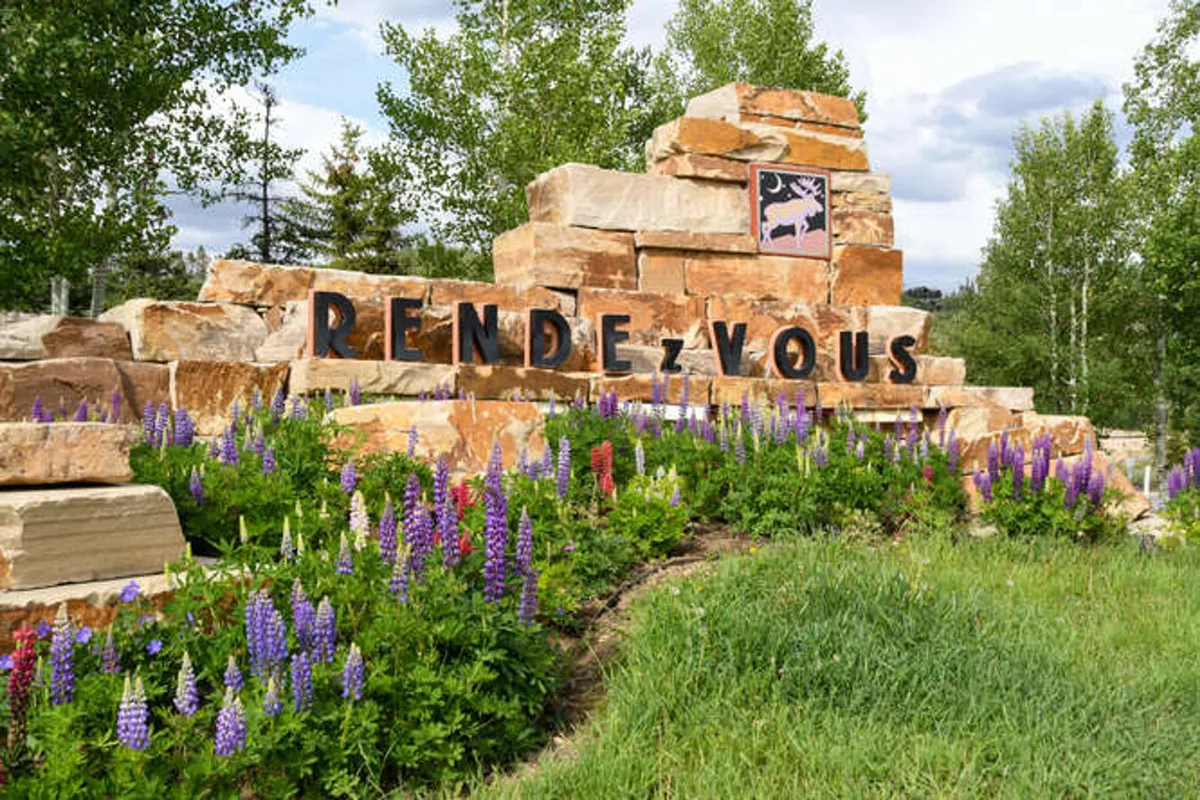 A beautiful stone structure with colorful seasonal flower displays and clear signage, set against a backdrop of nature. The image hints at local trails, community areas, and scenic walks—ideal for dog-friendly outings.