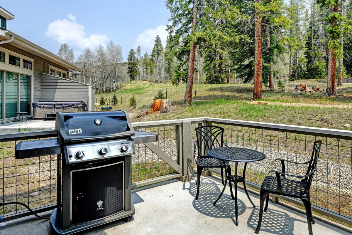 An inviting outdoor seating area with a grill and panoramic nature views sets the stage for leisurely afternoons and sunset gatherings. The setup is ideal for sipping coffee at sunrise or sharing stories at dusk, with comfortable furnishings that extend the living space outdoors.