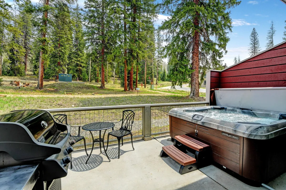 This image captures a welcoming outdoor patio featuring a bubbling hot tub, a sleek outdoor grill, and a bistro table set for al fresco dining. Surrounded by tranquil landscaping, the scene suggests both relaxation and social enjoyment, with plenty of space for lounging or gathering under the stars.